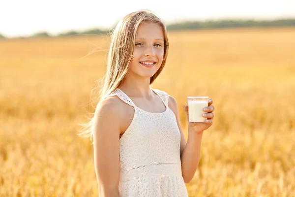 Ragazza felice con bicchiere di latte sul campo di cereali — Foto Stock