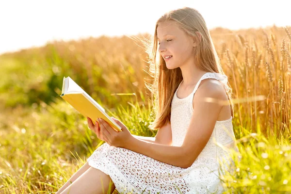 Sorridente jovem leitura livro sobre campo de cereais — Fotografia de Stock