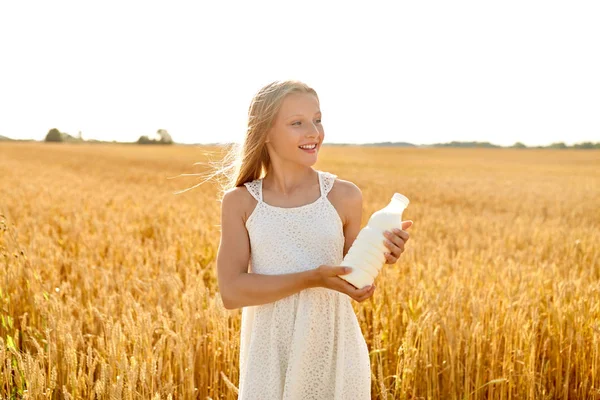 Ragazza felice con bottiglia di latte sul campo di cereali — Foto Stock