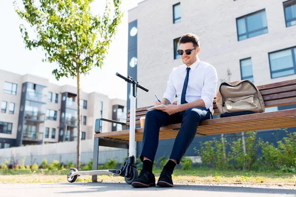 Usměvavý obchodník psaní do notebooků ve městě — Stock fotografie