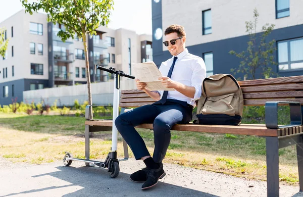 Hombre de negocios con scooter leyendo periódico en la ciudad —  Fotos de Stock