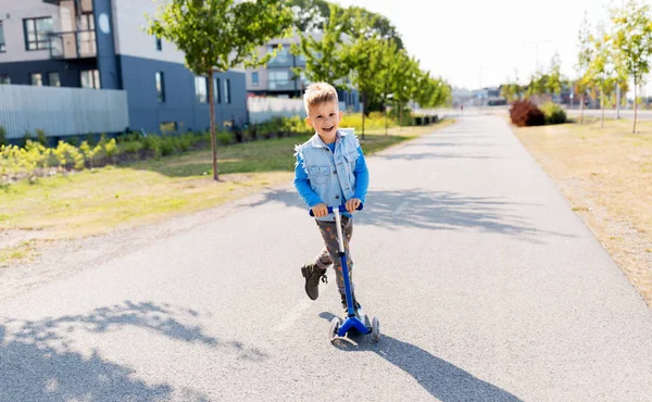 Gelukkig jongetje paardrijden scooter in stad — Stockfoto