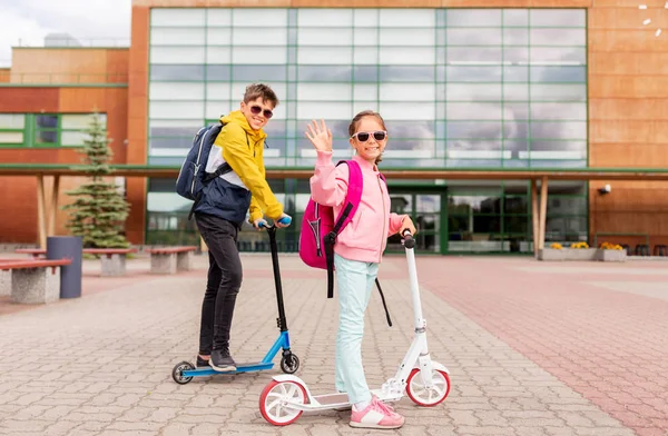 Niños de la escuela con mochilas a caballo scooters —  Fotos de Stock