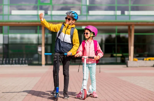 Happy school kids with scooters taking selfie — Stock Photo, Image