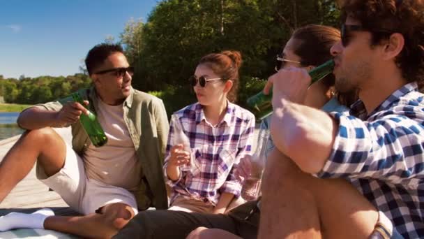 Vänner spottar drinkar på träbrygga vid sjön — Stockvideo