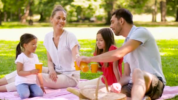 Boldog család ivás lé a piknik a parkban — Stock videók