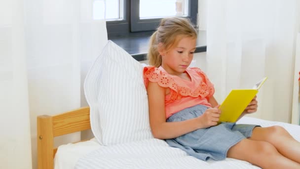 Ευτυχισμένο μικρό κορίτσι διαβάζοντας το βιβλίο στο σπίτι — Αρχείο Βίντεο