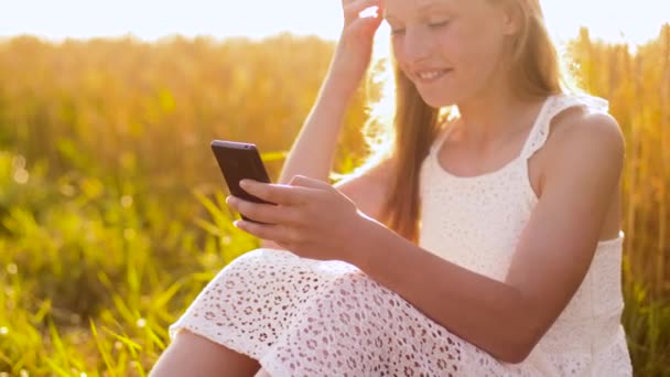 Счастливая молодая девушка со смартфоном на зерновом поле — стоковое видео