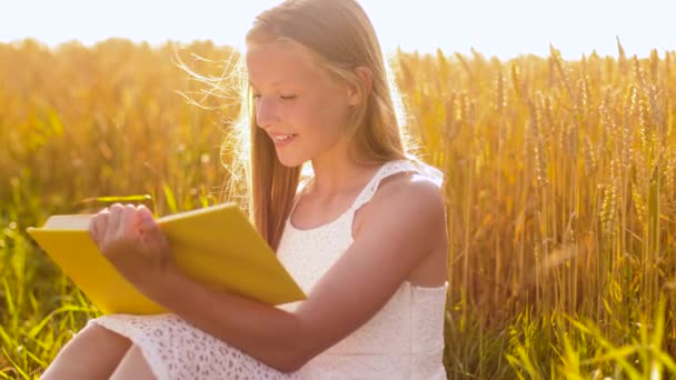 Glimlachend jong meisje lezen boek op graanveld — Stockvideo