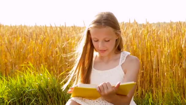 Mosolygós fiatal lány olvasatban könyvet gabona területén — Stock videók