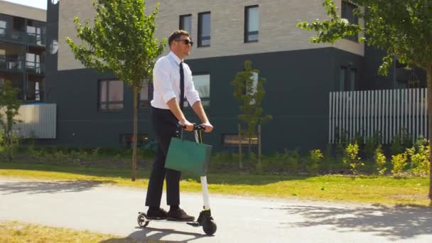 Geschäftsmann mit Einkaufstasche fährt Roller — Stockvideo
