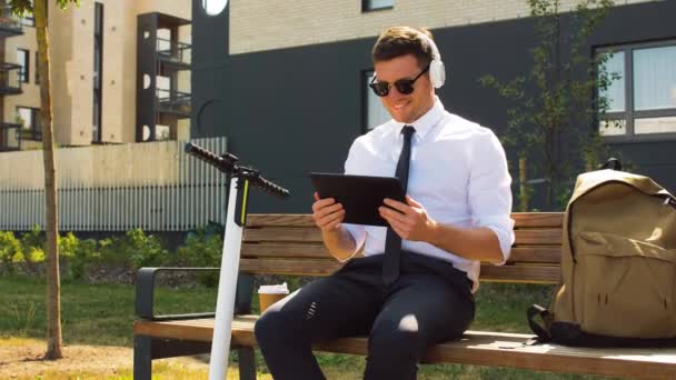 Empresário com tablet pc, fones de ouvido e café — Vídeo de Stock