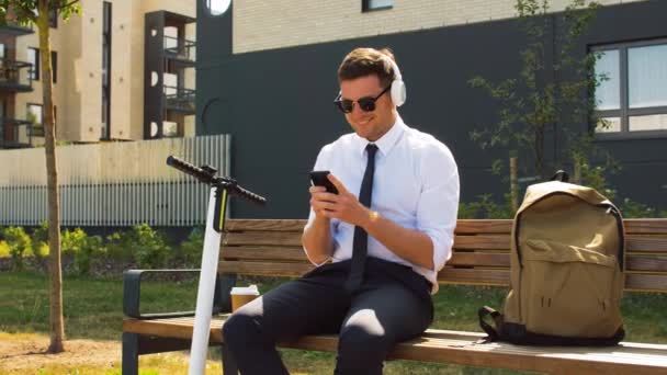 Hombre de negocios con teléfono celular, auriculares y scooter — Vídeos de Stock
