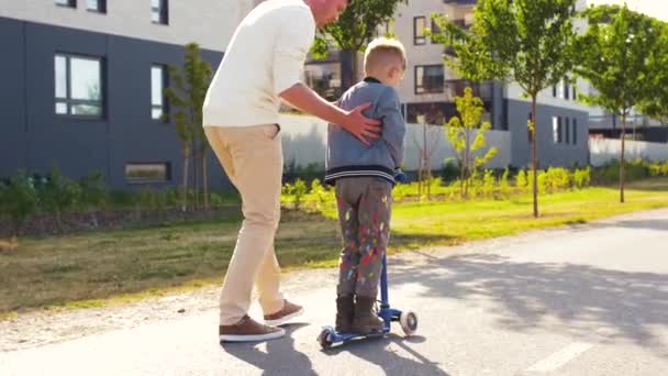 Pai feliz e filho montando scooter na cidade — Vídeo de Stock