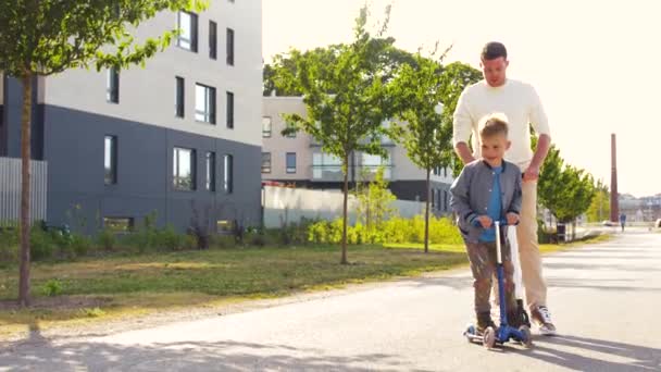 Lycklig far och son ridning skotrar i staden — Stockvideo