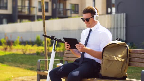 Hombre de negocios con tablet pc, auriculares y scooter — Vídeos de Stock