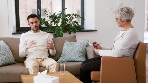 Senior psychologist giving water to man patient — Stock Video