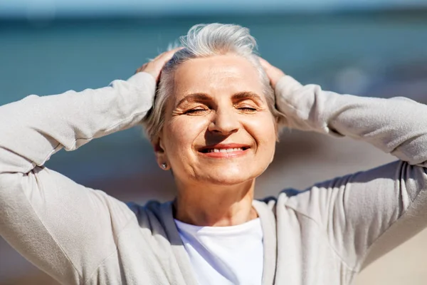 Portret van senior vrouw genieten van zon op het strand — Stockfoto