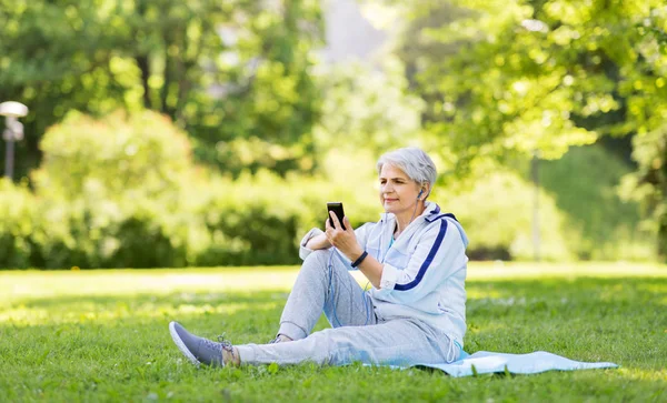 Спортивная пожилая женщина с наушниками и смартфоном — стоковое фото