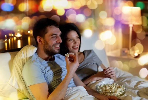 Pareja con palomitas de maíz viendo la televisión por la noche en casa —  Fotos de Stock