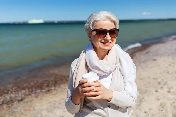 Senior femme boire du café à emporter sur la plage — Photo