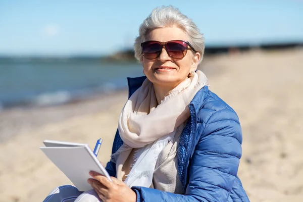 Senior femme écriture pour ordinateur portable sur la plage d'été — Photo