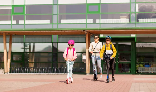 Bambini felici della scuola con la madre che guida scooter — Foto Stock