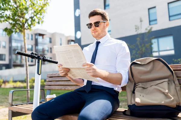 Hombre de negocios con scooter leyendo periódico en la ciudad — Foto de Stock