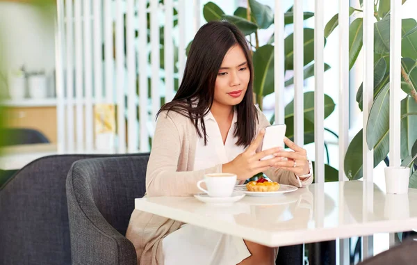 Азиатка со смартфоном в кафе или кофейне — стоковое фото