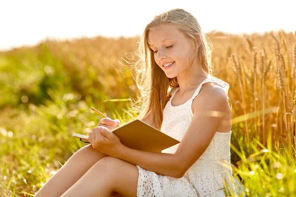 Chica sonriente escribiendo a diario en el campo de cereales — Foto de Stock