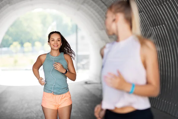 Kvinnor eller kvinnliga vänner med hörlurar som kör — Stockfoto