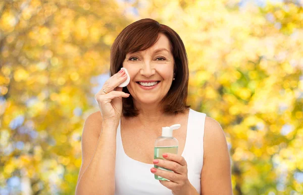 Senior kvinna rengöring ansikte av lotion på bomullspad — Stockfoto