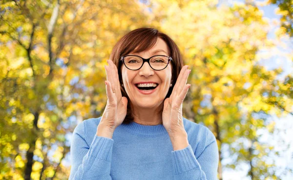 Mulher sênior em óculos chamando sobre parque de outono — Fotografia de Stock