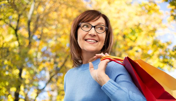 Senior Kvinna med shoppingväskor över höst parken — Stockfoto