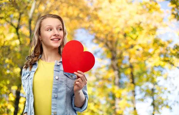 Adolescente sonriente con corazón rojo en el parque de otoño — Foto de Stock