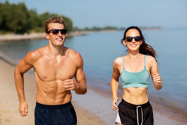 Koppel in sport kleding lopen langs op het strand — Stockfoto