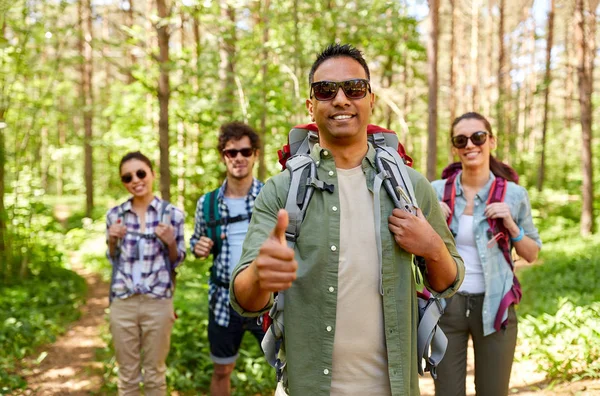 Friends with backpacks showing thumbs up in forest — Stock Photo, Image