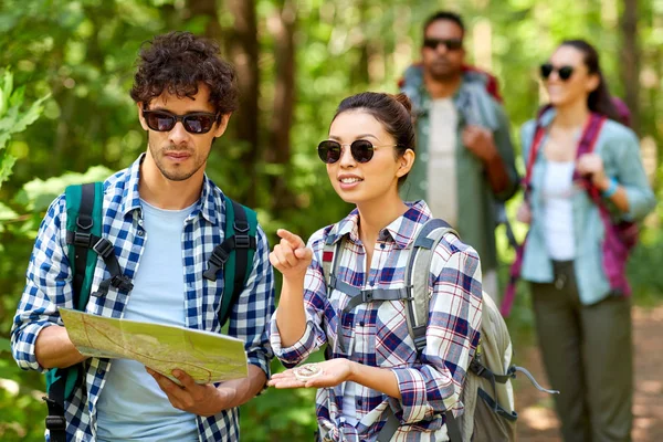 Barátok térképpel és hátizsákok túrázás az erdőben Stock Kép