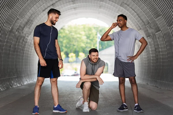 Male friends with earphones training outdoors — Stock Photo, Image