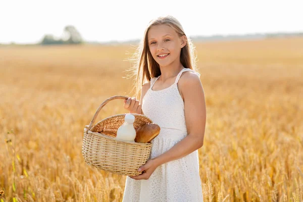 Ragazza con pane e latte in cesto sul campo di cereali — Foto Stock