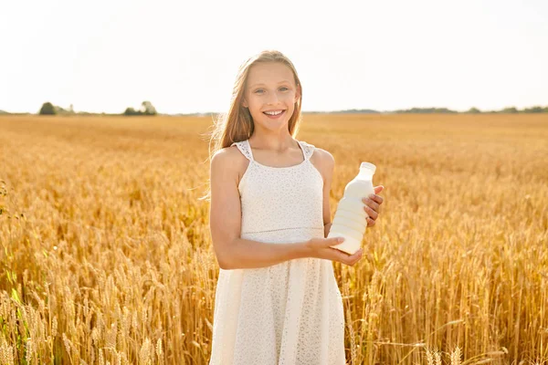 Chica feliz con botella de leche en el campo de cereales — Foto de Stock