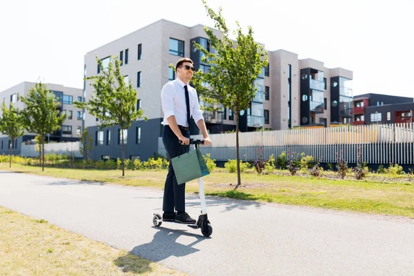 Hombre de negocios con bolsa de compras a caballo scooter —  Fotos de Stock