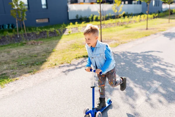 Gelukkig jongetje paardrijden scooter in stad — Stockfoto