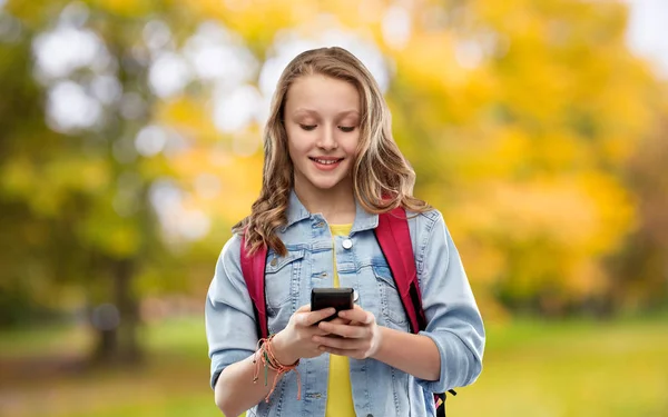 Школьница со школьной сумкой и смартфоном — стоковое фото