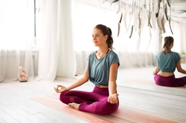 woman meditating in lotus pose at yoga studio clipart