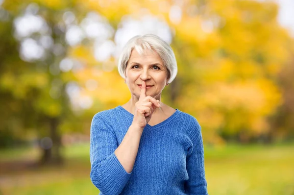 Пожилая женщина делает тихий жест в осеннем парке — стоковое фото