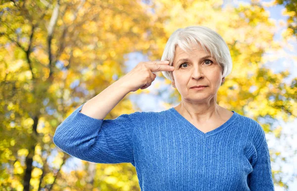 Anciana haciendo gesto de arma de dedo en el parque de otoño — Foto de Stock