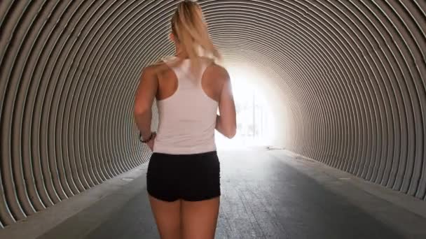 Молодая женщина бежит в туннеле приглашая присоединиться к ней — стоковое видео