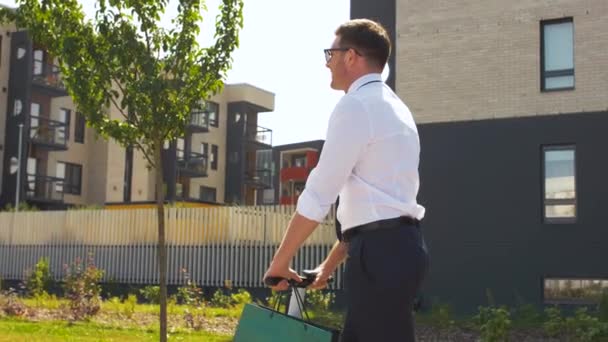Uomo d'affari con shopping bag equitazione scooter — Video Stock