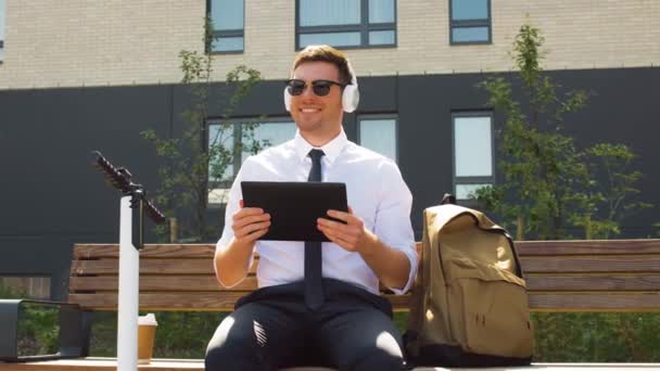 Homem de negócios com tablet pc, fones de ouvido e scooter — Vídeo de Stock
